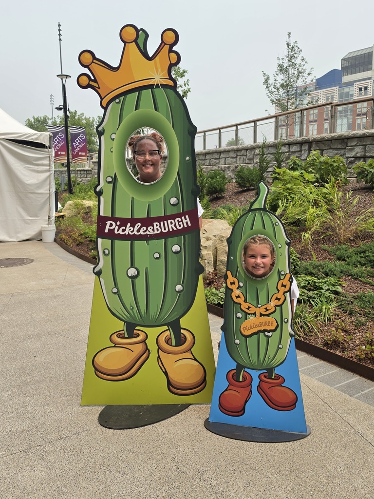 Kasidi and a older woman posing for a picture with pickle standees