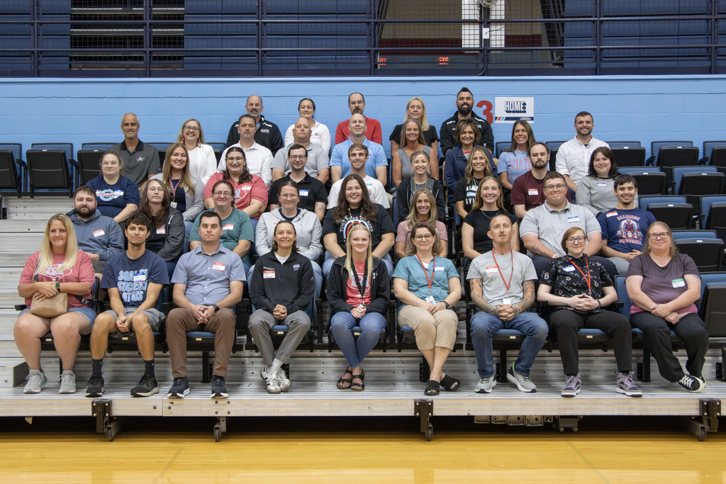 A group picture of all the new staff members siting in bleachers