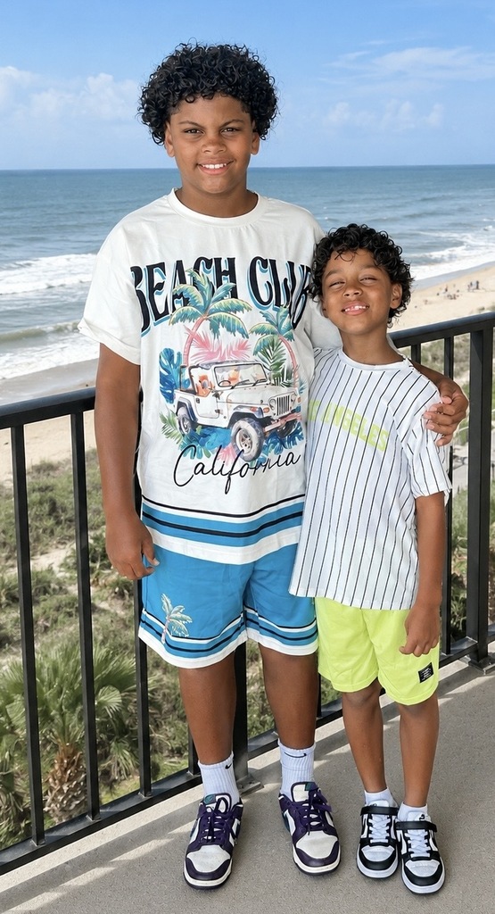 Tyler standing with his little brother on a balcony over looking the beach