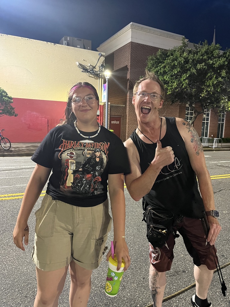 Harleigh smiling while standing with someone who is giving a thumbs up