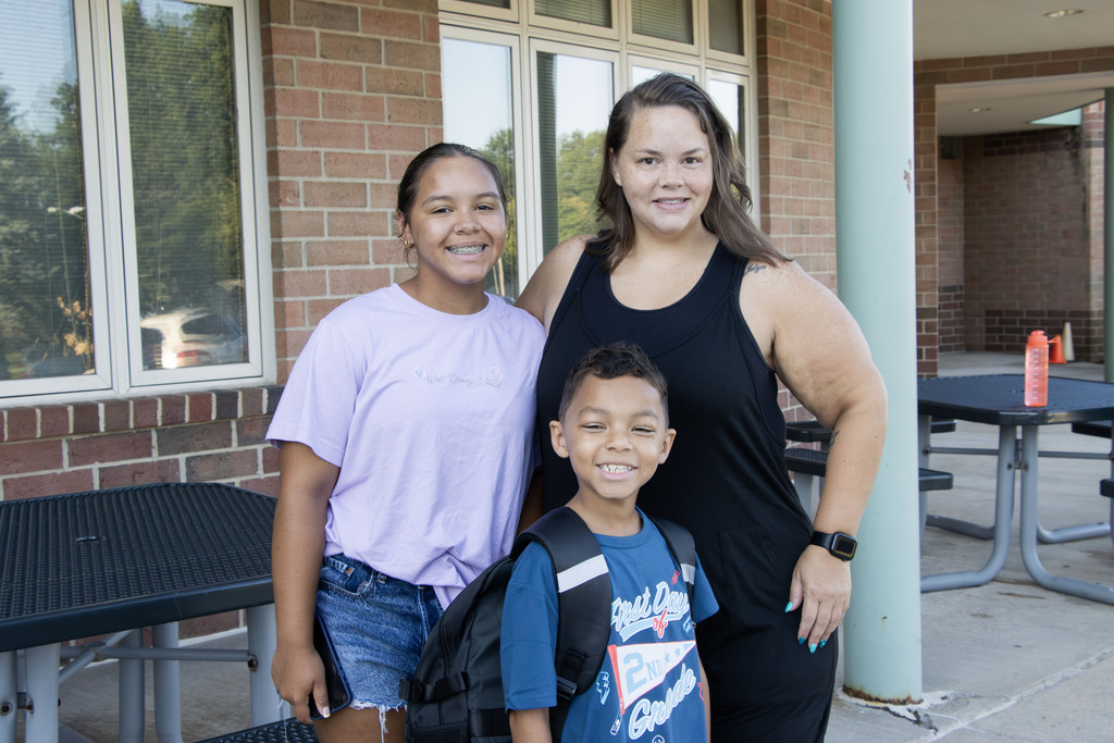 A mom standing with her daughter and son while smiling