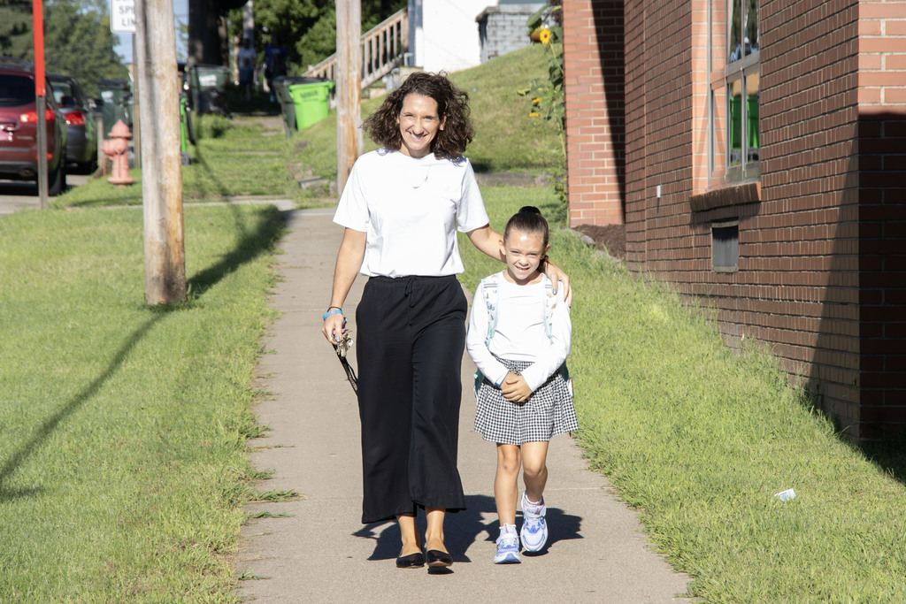 A mom walking her daughter to school while smiling