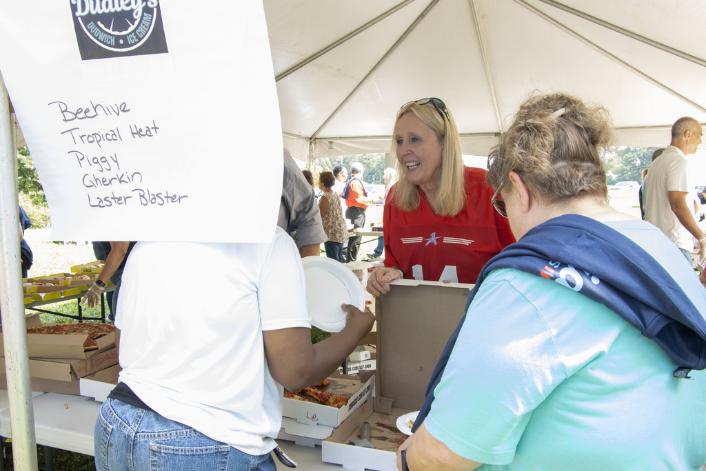 A staff member serving pizza to other aviator staff members
