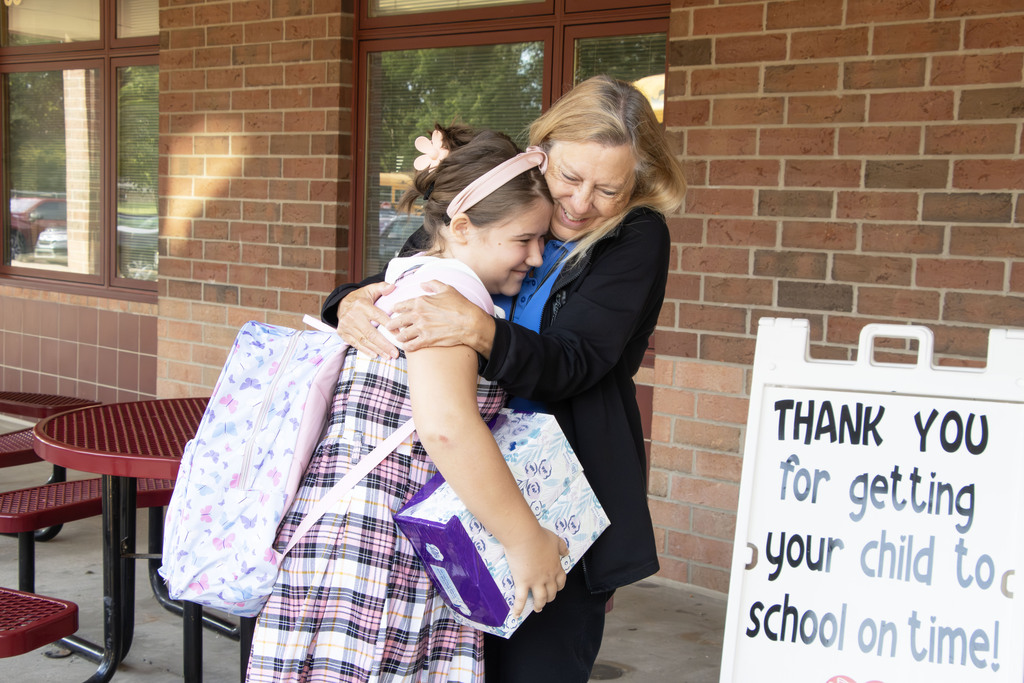 A student hugging a staff member while both smile
