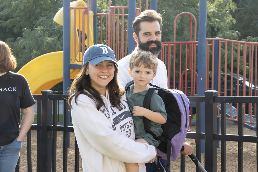 A family smiles while walking past the play ground.