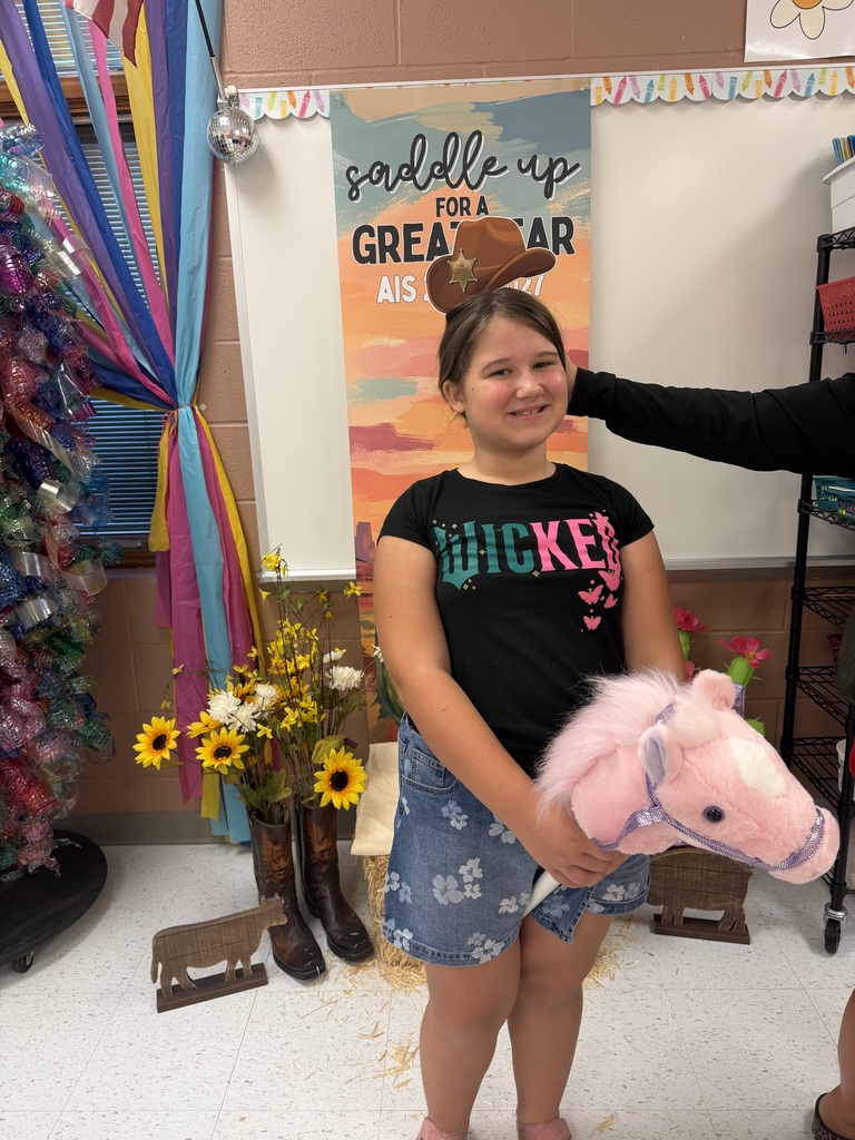 A student sitting in front of a "Saddle Up for a great year AIS" banner