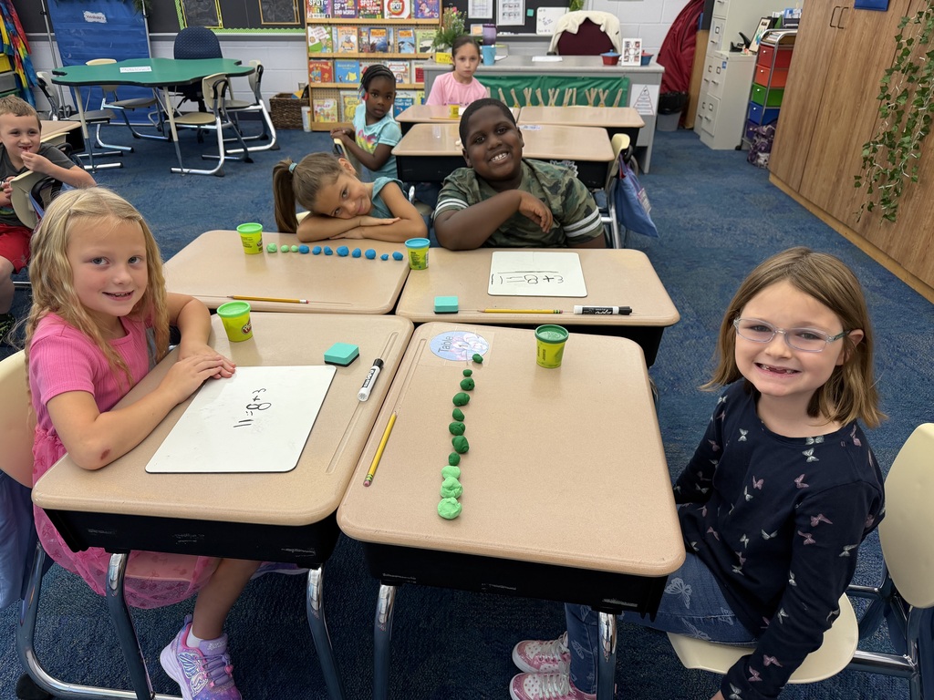 Four students sit around a table with play-doh on the table