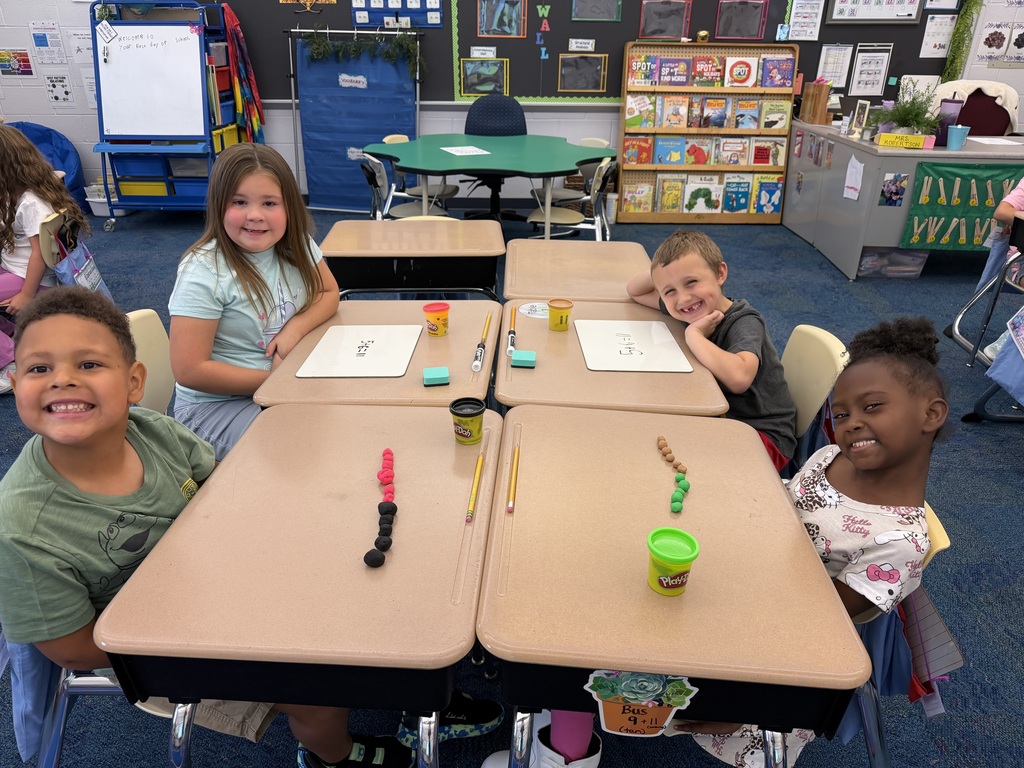Four students sit around a table with play-doh on the table