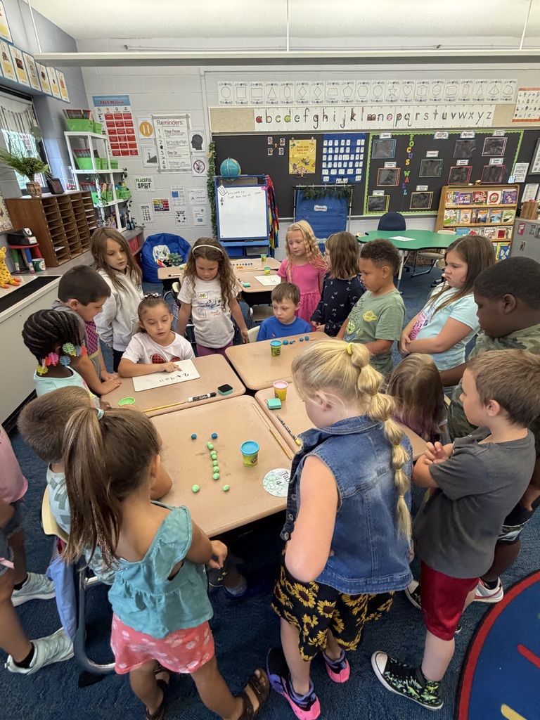 Students sit around a table with play-doh on the table