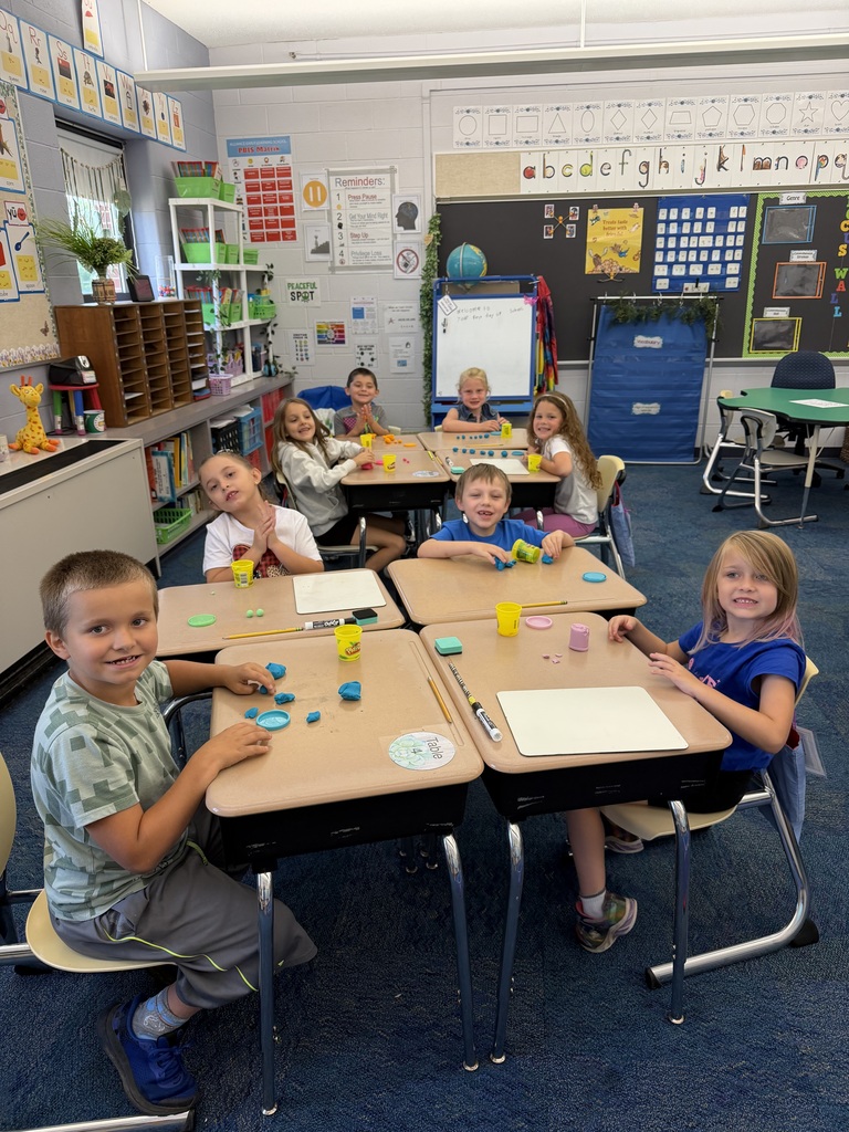 Four students sit around a table with play-doh on the table