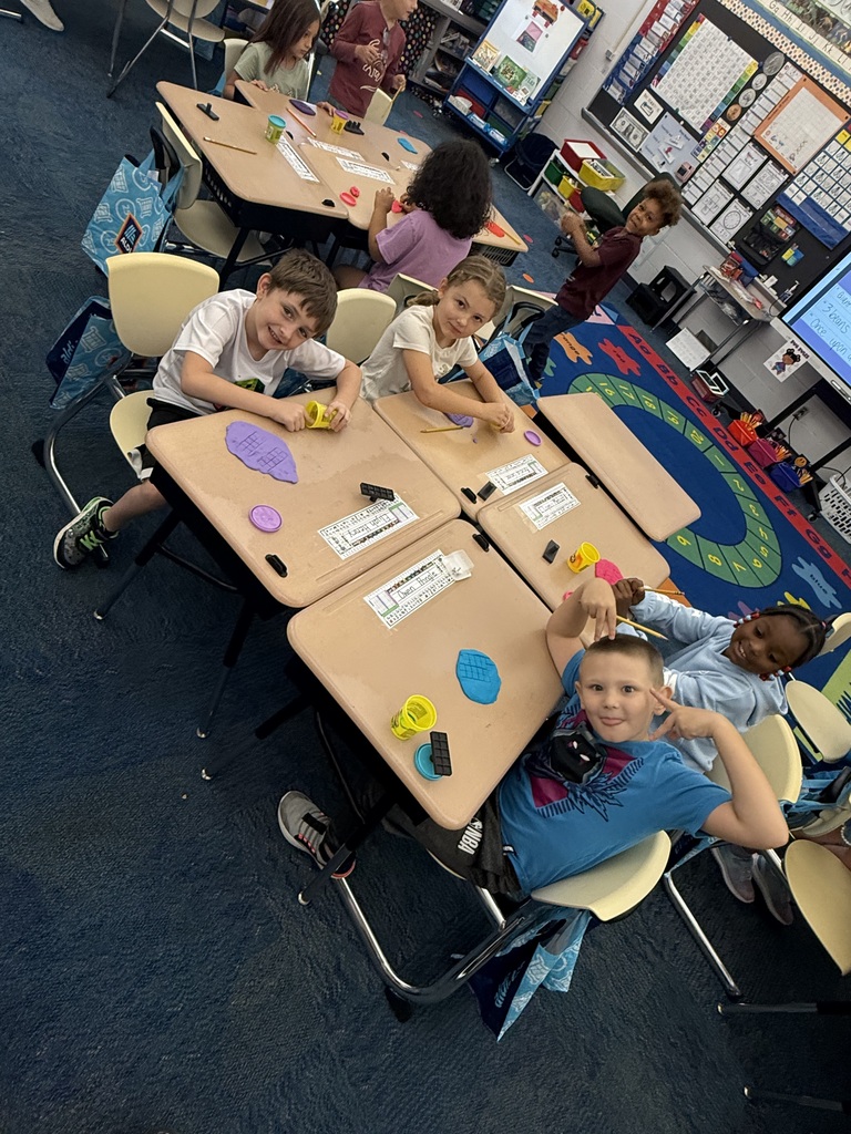 Elementary students use colorful Play-Doh and ten-frame grids to practice counting during a classroom center activity.