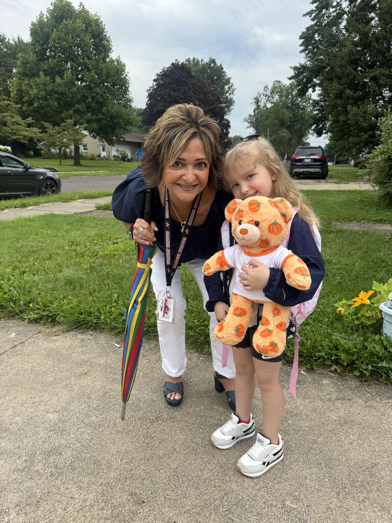 Mrs. G standing with Charleigh for a picture while holding an orange build a bear with pumpkins on it.