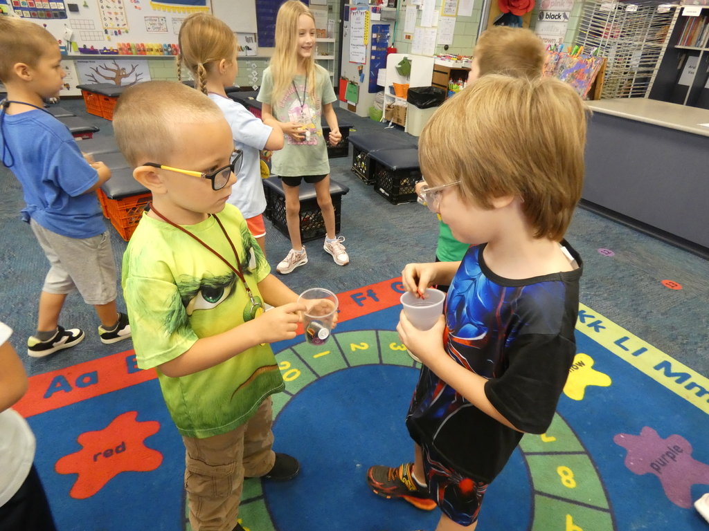 two students holding plastic cups and filling them with coins