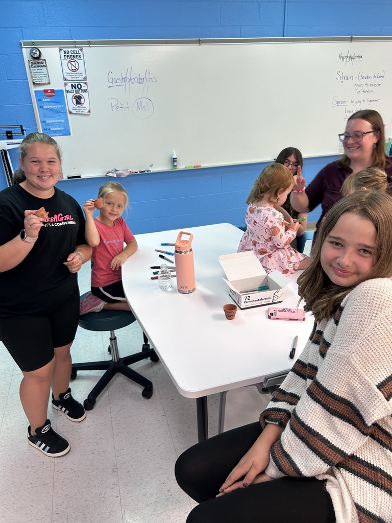 A group of student sit at a table together while smiling 