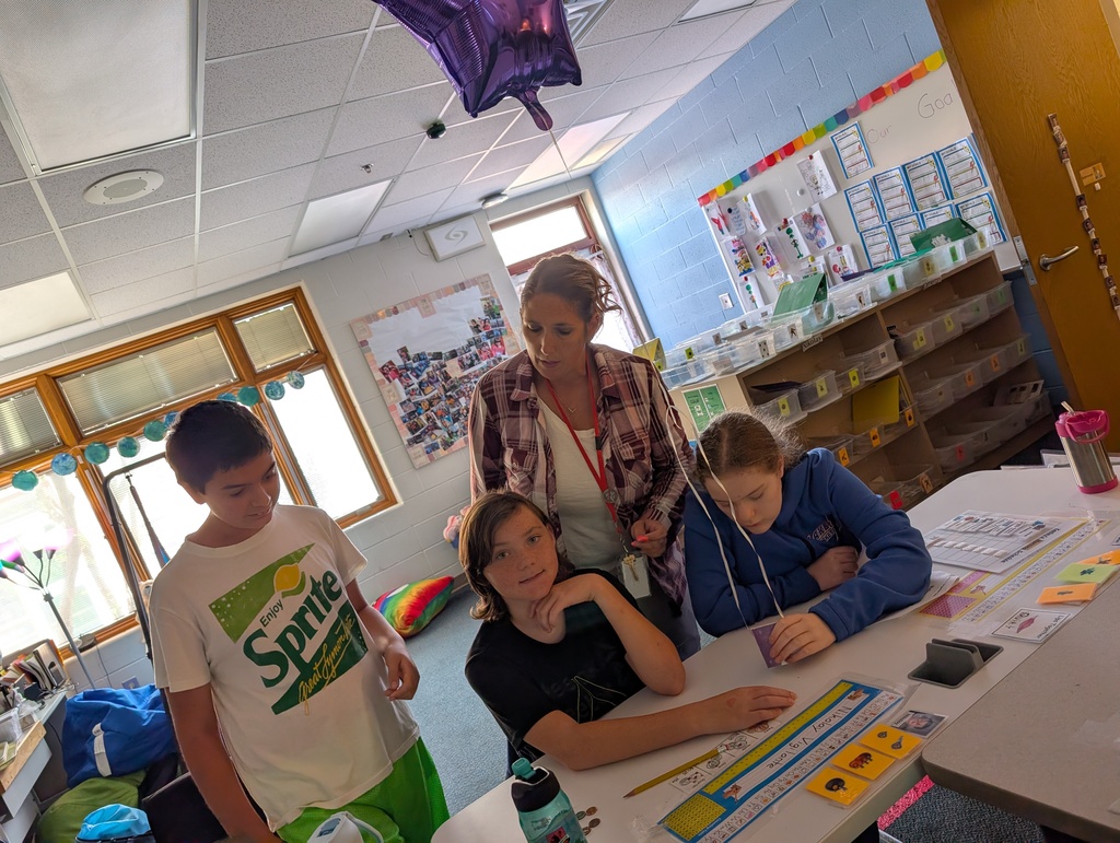 Students in a classroom hold balloons and pennies while doing a science experiment