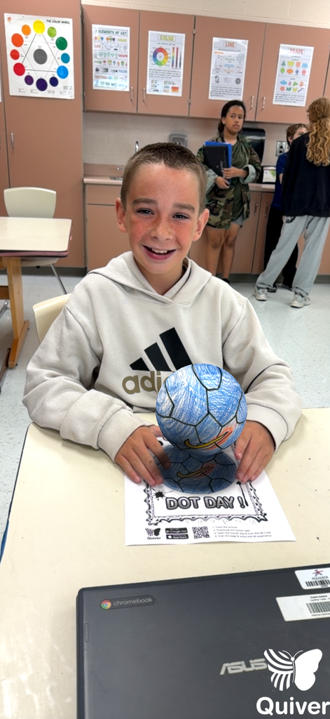 A student stands while holding what appears to be a 3-d generated sphere she used with the quiver app of the dot they created