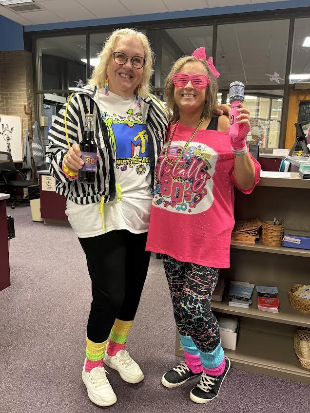 Staff members dressed in bright colors and 80s themed outfits