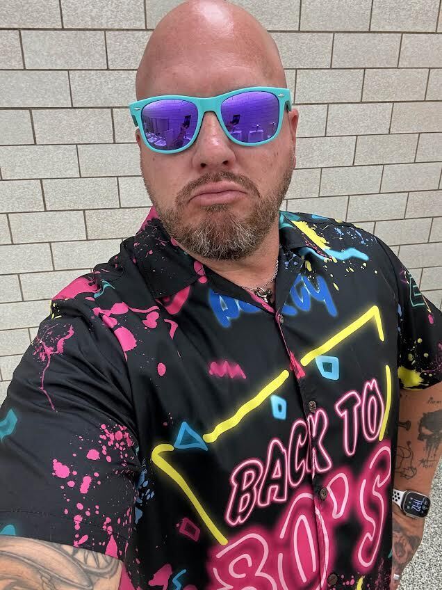 Staff members dressed in bright colors and 80s themed outfits
