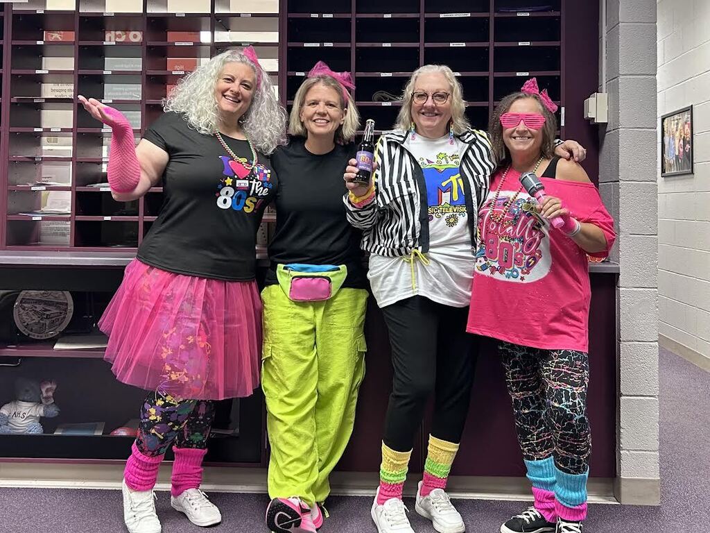 Staff members dressed in bright colors and 80s themed outfits