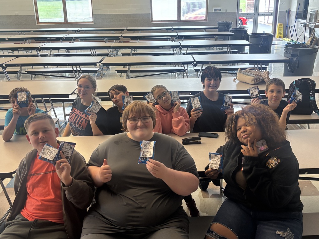 The students in builders club smile while holding up the treats they put together for the custodians