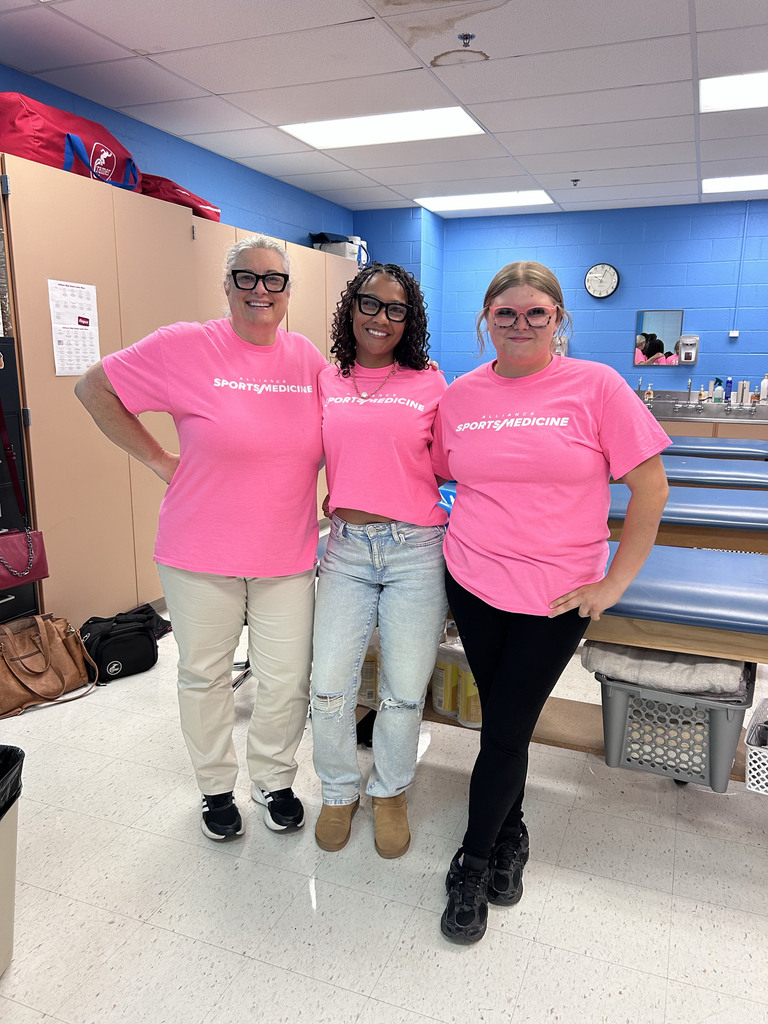 A teacher and two students wearing matching pink tshirts