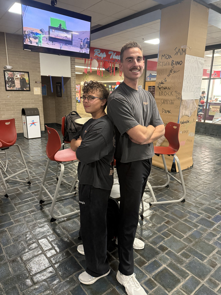 A student and a teacher standing back to back dressed alike for twin day