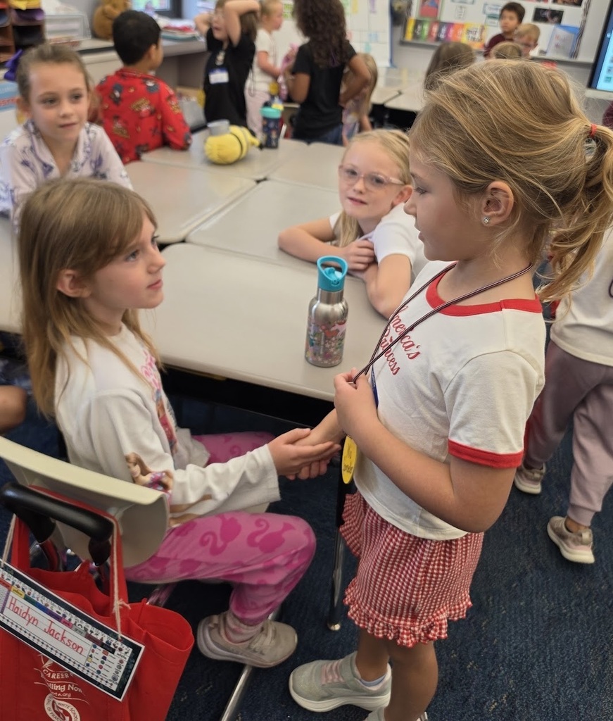 two students shake hands while others watch in the background
