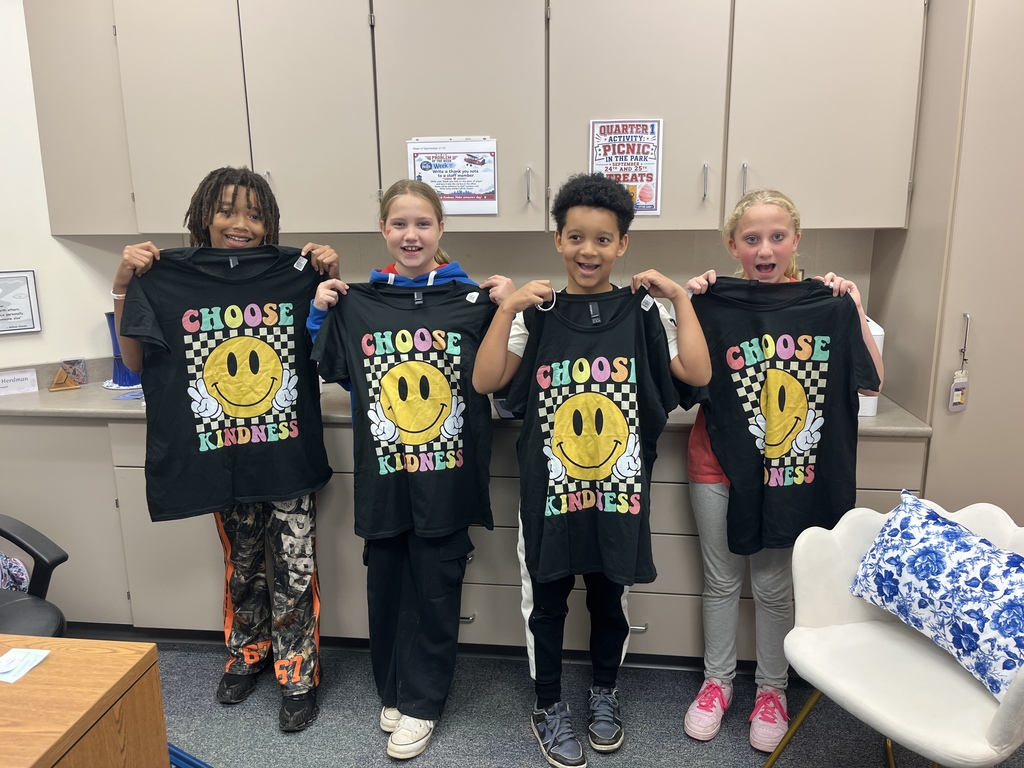 Four students hold up black tshirt with a smiley face and the words "Choose Kindess"