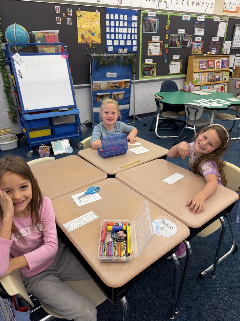 Three students sitting at desk coloring bookmarks
