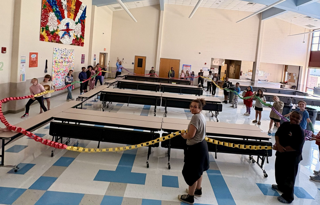 Students hold the chain around the cafeteria to see how long it is