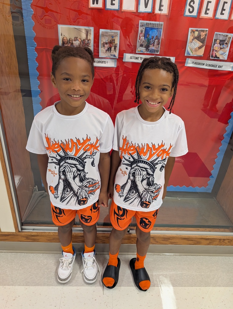 Two students dressed the same in matching white shirts and orange shorts