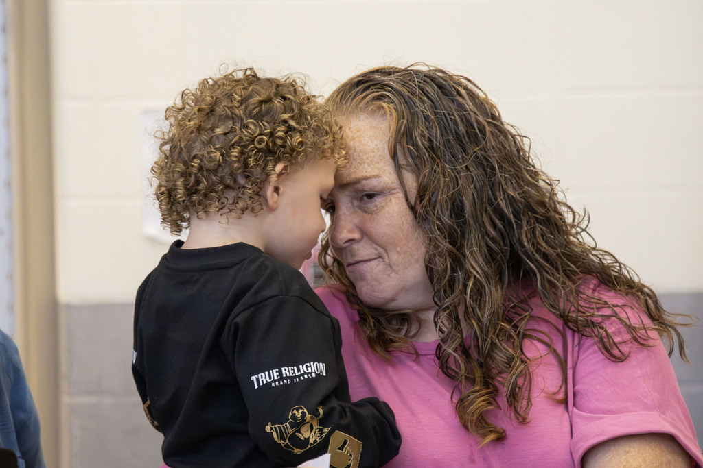 A grandmother holds her grandchild while touching foreheads together and smiling