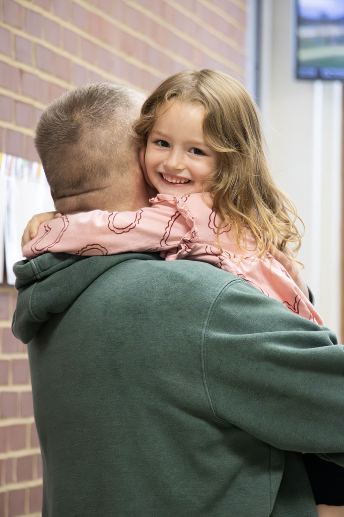 A grandfather is hugging while she smiles looking over his shoulder