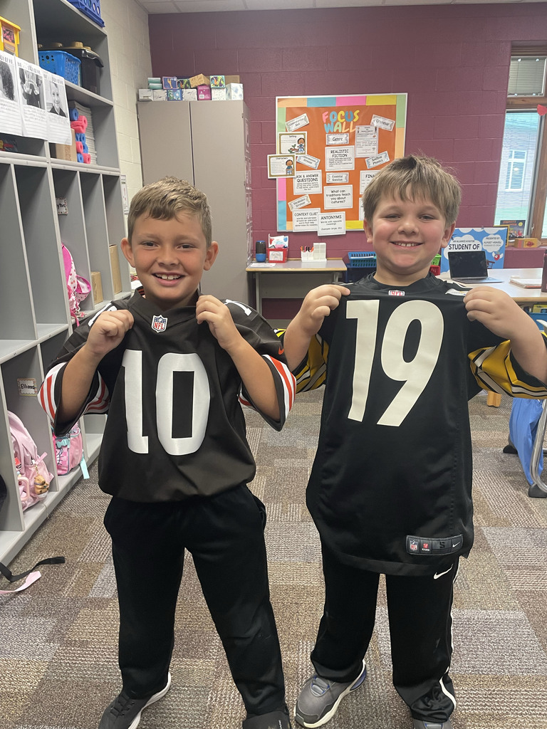 A student dressed like a Cleveland browns player and another dressed like a Pittsburgh Steelers player pose for a picture