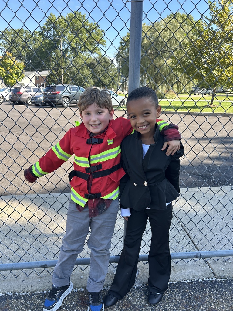 A student dressed like a firefighter and another dressed like a business woman pose for a picture