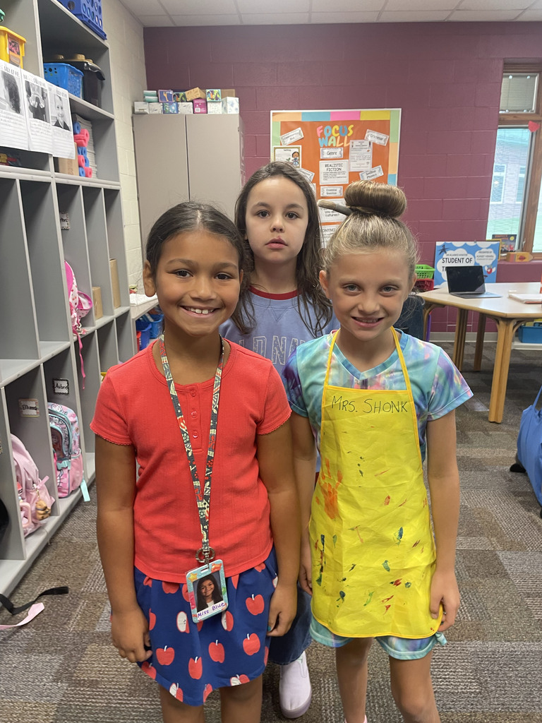 A student dressed like a teacher and another one dressed like an artist smile for a picture