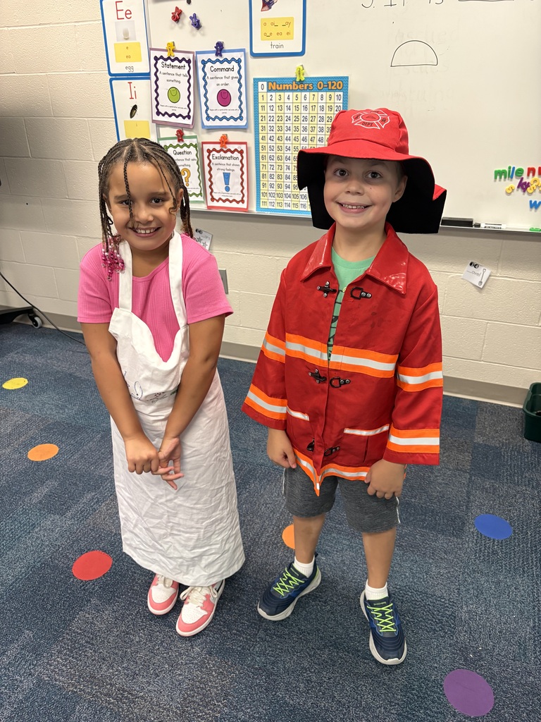 A student dressed like a chef and another dressed like a firefighter pose for a picture