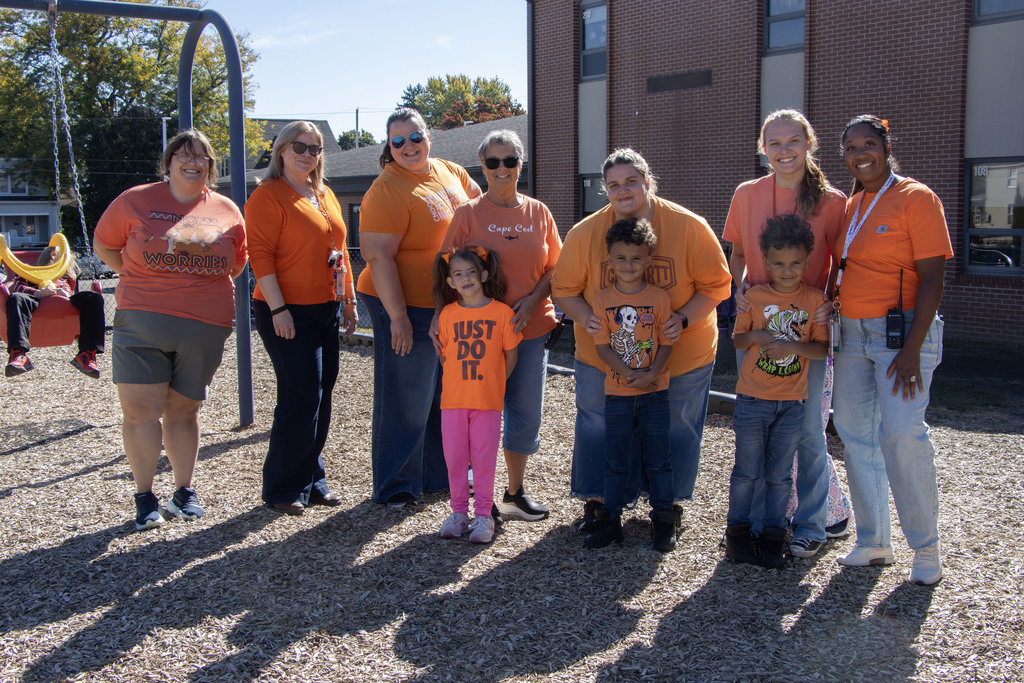 A group fo students and staff members in orange post of a picture on the playground