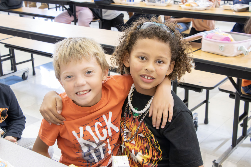 Two students pose for a picture while wearing orange shirts