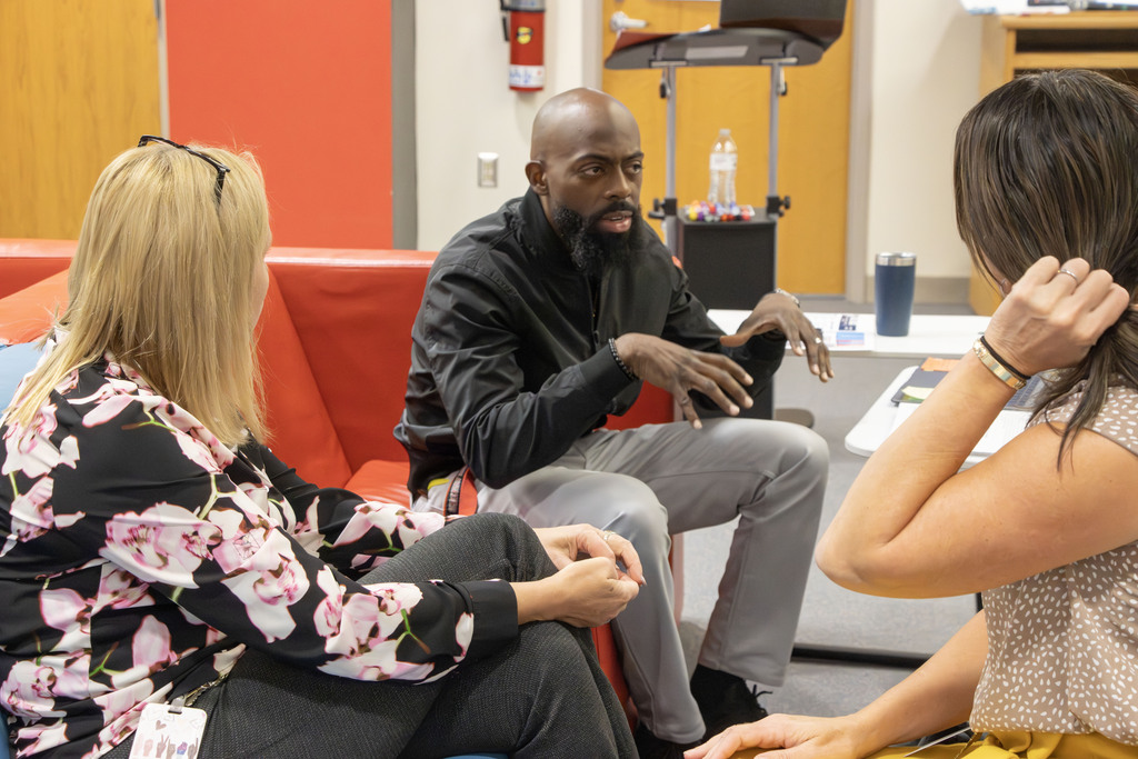 Two administrators talk with an ACS staff member who is part of the 5A group