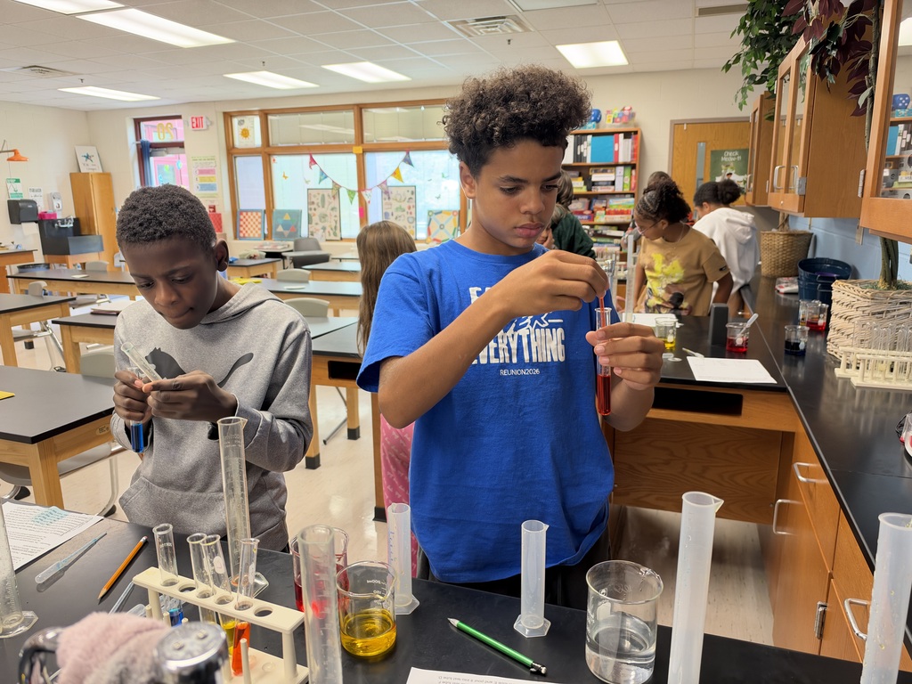Two students hold test tubes in a science classroom