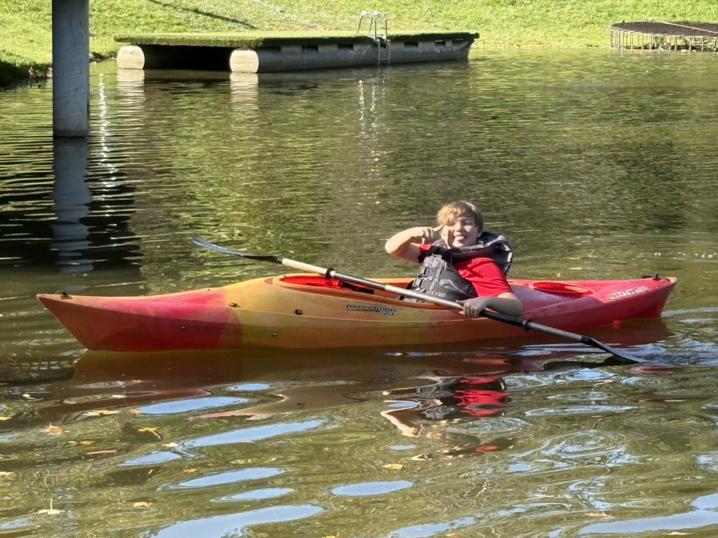 A student gives a thumbs up while in a kayak on the water
