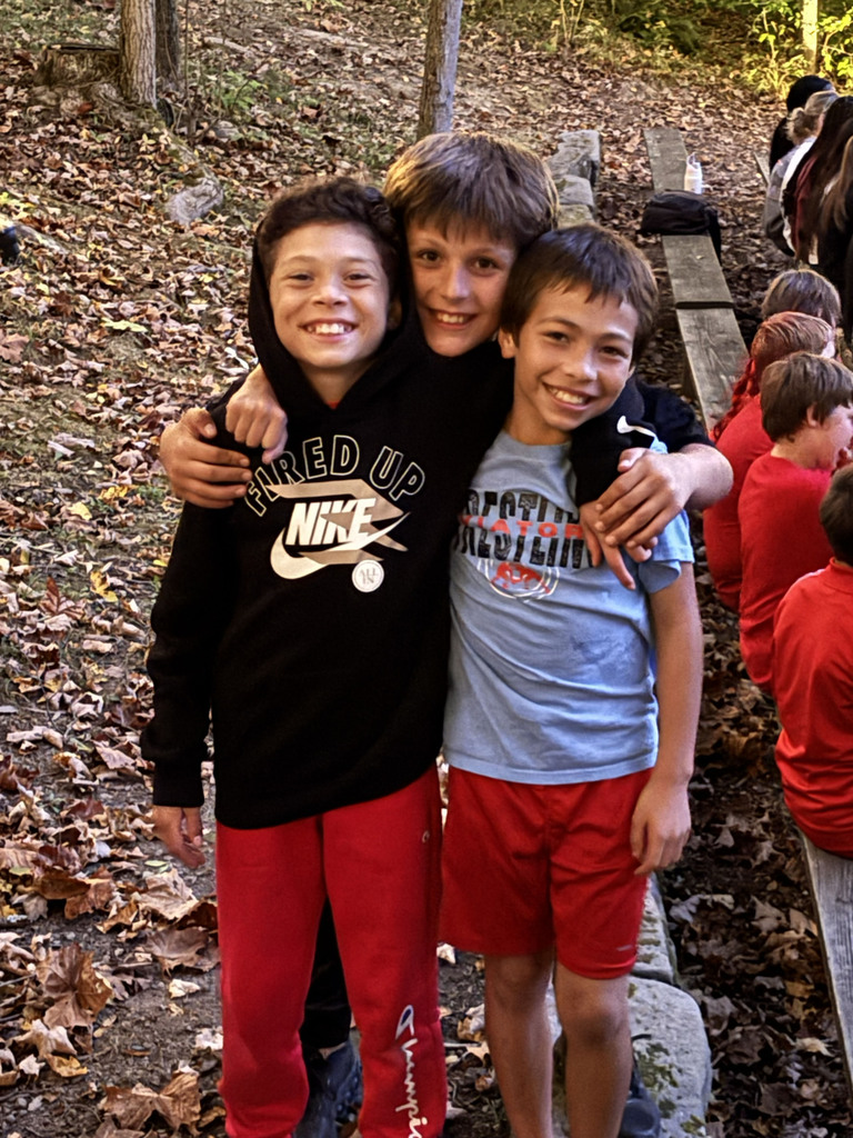 Three students with their arms around each other smile for a picture