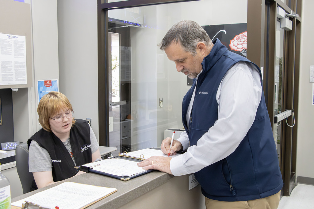 Mr. Gress checks in at the front desk with the student receptionist