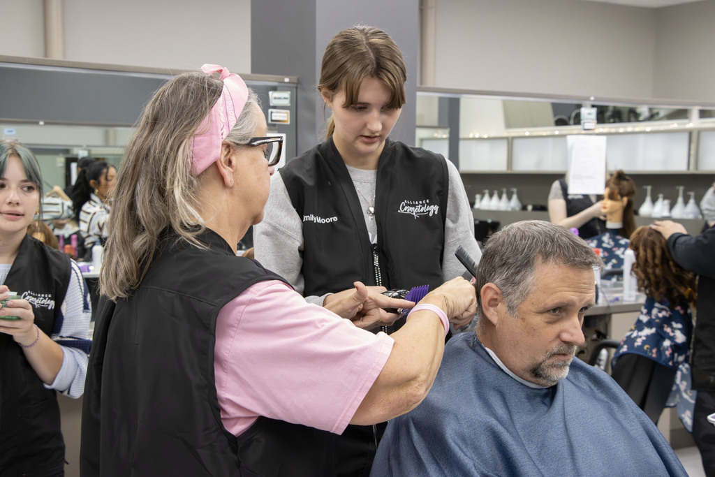 Mr. Gress sits while Emily and the teacher Mrs. Scanlon discuss how to cut his hair