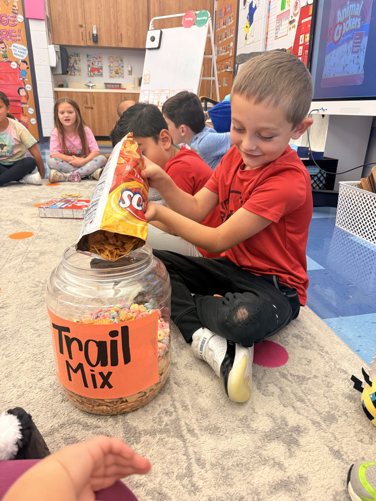 A student pours a bag of Fritos in to a container labeled trail mix
