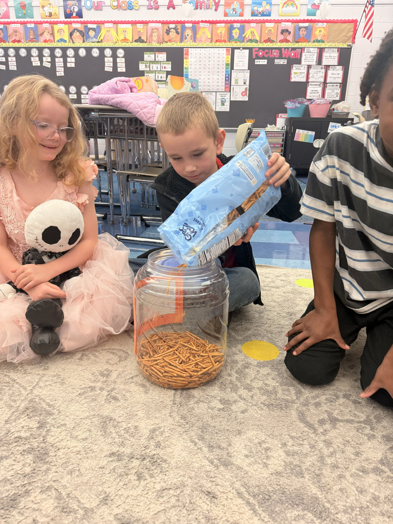 A student pours treats in a container while two other students watch.
