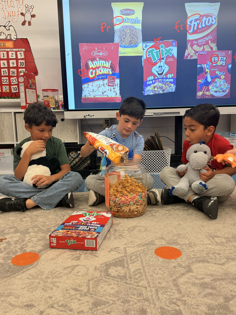 A student pours treats in a container while two other students watch.