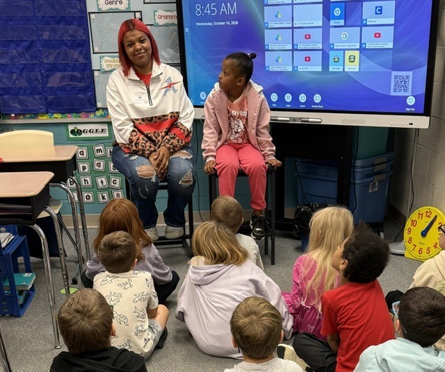 Malina and her daughter sit in from of the class while she talks about her job