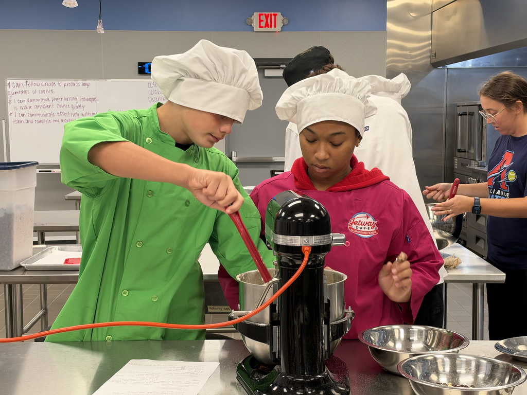 Two students make dough using a stand mixer